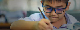 Boy with glasses writing